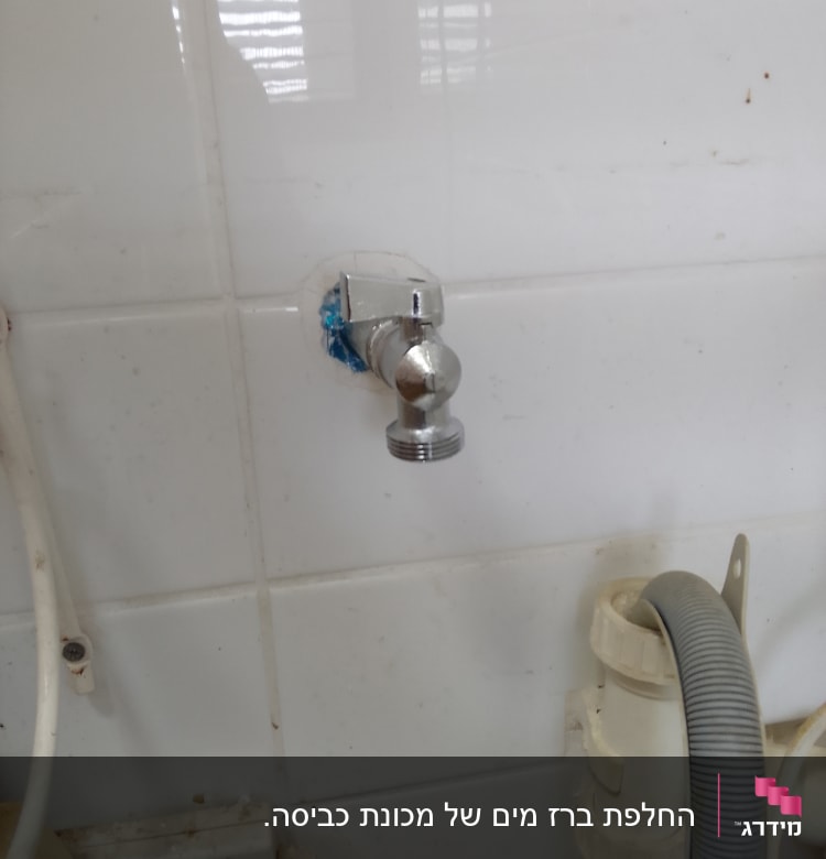 ברז מתכת מותקן על קיר אריחים לבן